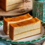 Two slices of golden and fluffy Castella cake with a smooth top, served on a decorative plate, highlighting the perfect texture of the Easy Castella Cake Recipe.