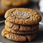 Stack of homemade molasses cookies on a gray plate, with cracked tops and a sugar dusting, in a cozy, natural light setting.