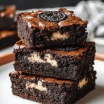 Stack of three fudgy, homemade Oreo brownies with a crackly top, creamy Oreo chunks inside, and a whole Oreo baked into the top brownie.
