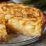 Homemade Passover potato pie with a golden crust and creamy potato filling, served in a glass dish with one slice removed.
