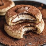 Homemade Tiramisu Cookies with creamy mascarpone filling, dusted generously with cocoa powder on a rustic dark plate.