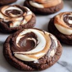 Homemade Chocolate Marshmallow Swirl Cookies of toasted marshmallow and melted chocolate on a marble surface, soft and fudgy with a gooey, golden top.