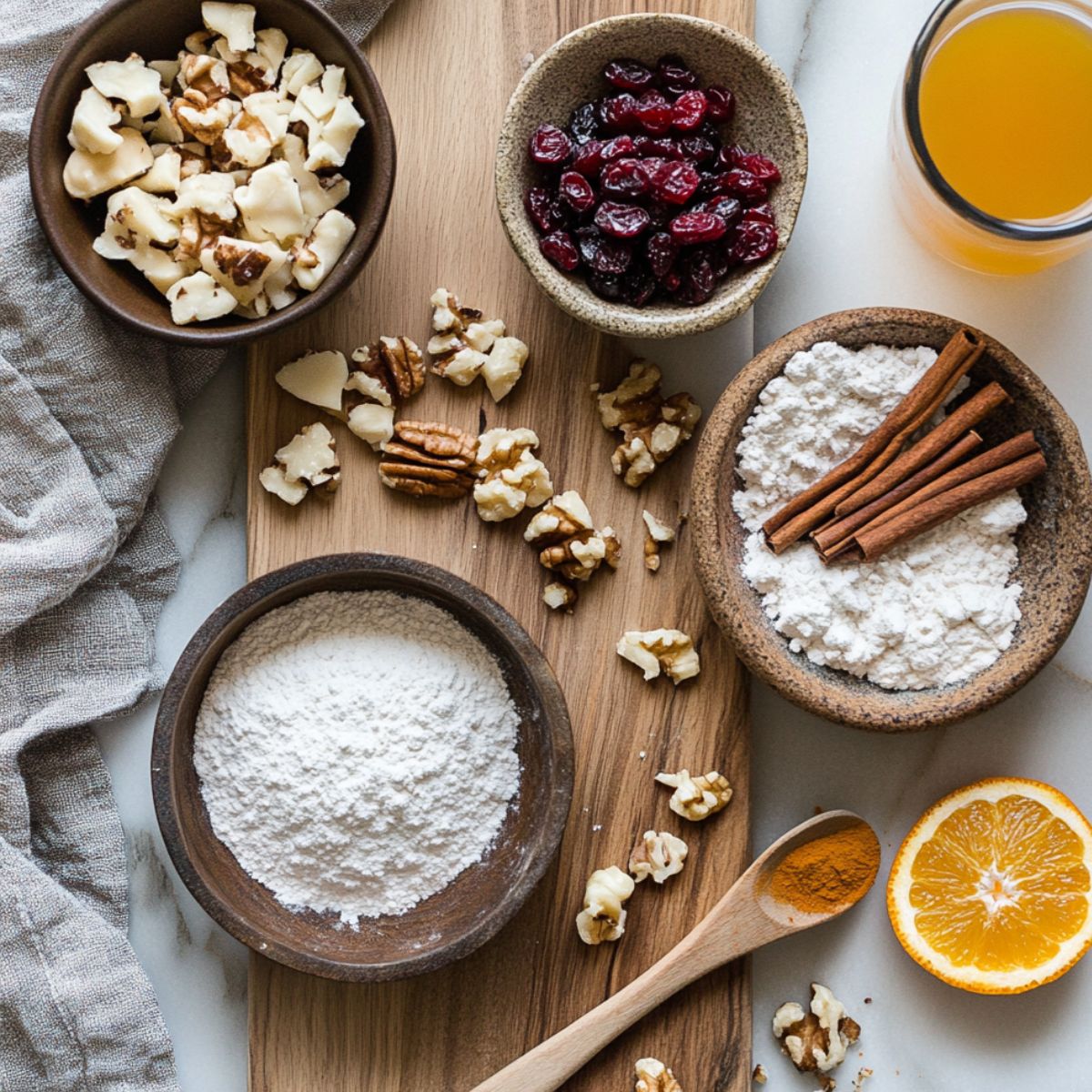 Optional ingredients for cranberry orange cookies, including chopped nuts, dried cranberries, powdered sugar, cinnamon sticks, orange juice, and half an orange on a rustic wood board.