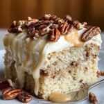 Homemade Butter Pecan Tres Leches Cake with whipped cream, caramel drizzle, and toasted pecans on a white plate.
