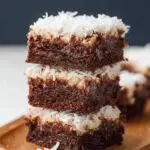 Homemade Coconut Brownies on a wooden tray, with moist chocolate layers and shredded coconut topping.