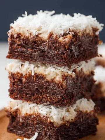 Homemade Coconut Brownies on a wooden tray, with moist chocolate layers and shredded coconut topping.