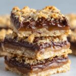 The Best Oatmeal Fudge Bars stacked on parchment, showing a golden oat base, thick chocolate layer, and crumbly oat topping.