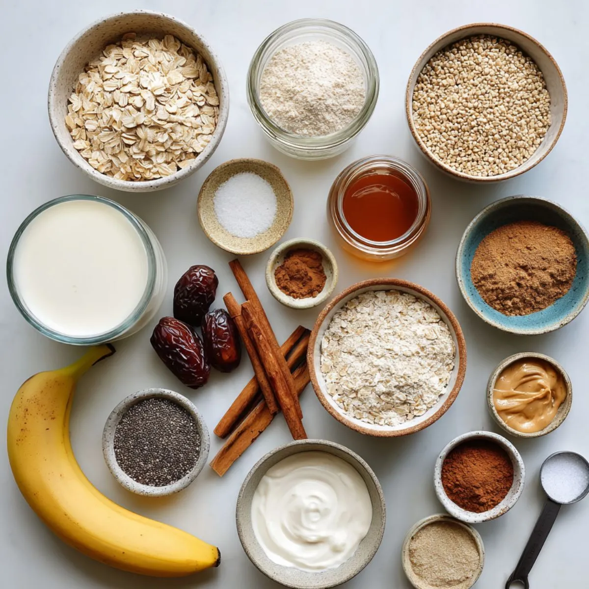 Blended oats ingredients flat lay: oats, milk, banana, dates, honey, cinnamon, peanut butter, yogurt, chia, flax.