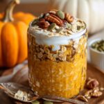 Healthy Pumpkin Overnight Oats Recipe in a jar topped with yogurt, pecans, pumpkin seeds, and granola.