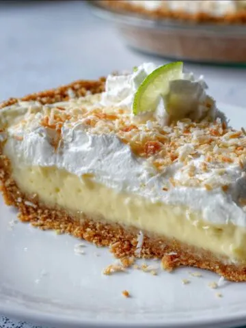 Homemade Atlantic Beach Pie Recipe on a white plate with a golden cracker crust, creamy lemon-lime filling, fluffy whipped cream, toasted coconut topping, and a small lime wedge garnish.