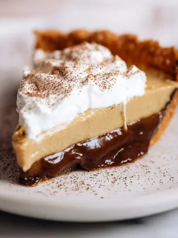Homemade Coffee Custard Pie Recipe with flaky crust, creamy coffee filling, whipped cream topping, and cocoa dusting on a white plate with red rim.