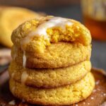 Homemade Cornbread Cookies Recipe with cinnamon sugar, one bitten to reveal a soft interior, topped with a cinnamon glaze. Warm, rustic background.