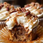 Close-up of a homemade pecan pie cupcakes with creamy frosting, caramel drizzle, and chopped pecans on top, showing a gooey brown pecan filling inside a moist golden cupcake.