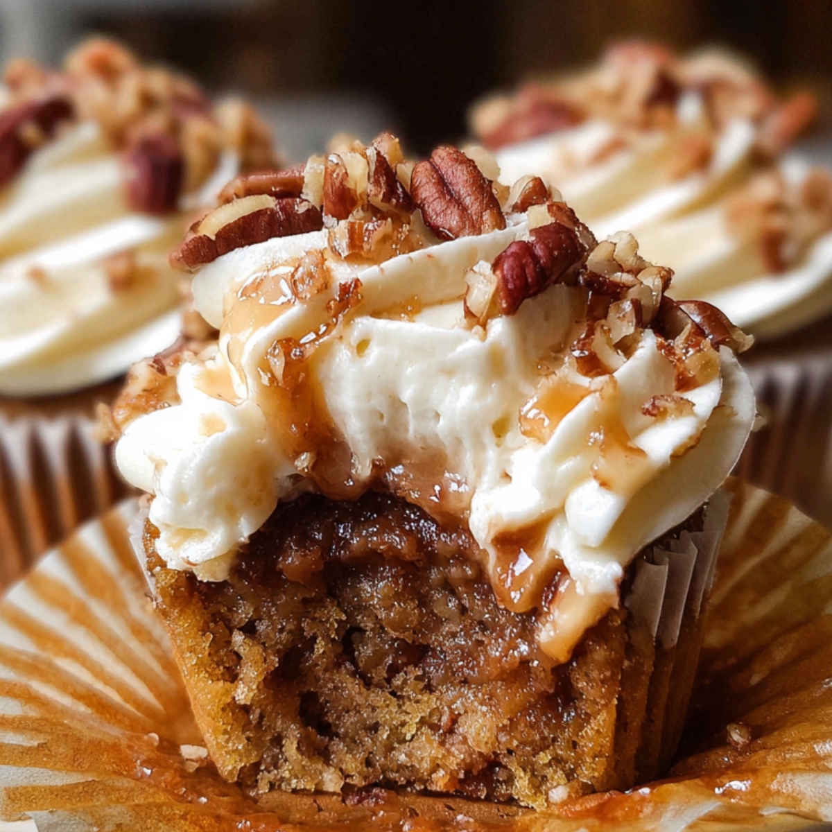 Close-up of a homemade pecan pie cupcakes with creamy frosting, caramel drizzle, and chopped pecans on top, showing a gooey brown pecan filling inside a moist golden cupcake.