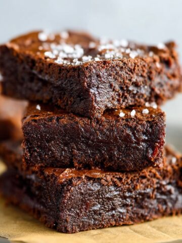 Homemade Chickpea Brownies on parchment paper with melted chocolate oozing between layers, homemade and gooey.