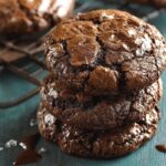 Homemade Chocolate Brownie Cookies with cracked, glossy tops, set against a teal background, capturing a homemade feel.