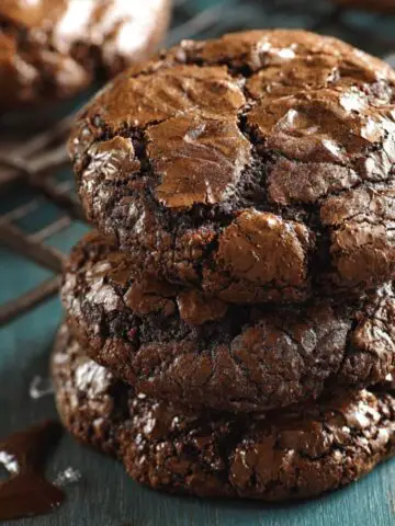 Homemade Chocolate Brownie Cookies with cracked, glossy tops, set against a teal background, capturing a homemade feel.