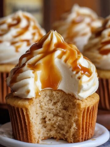 Homemade Harry Potter Butterbeer Cupcakes with creamy frosting and golden caramel drizzle, showing a soft, fluffy interior where a bite has been taken.