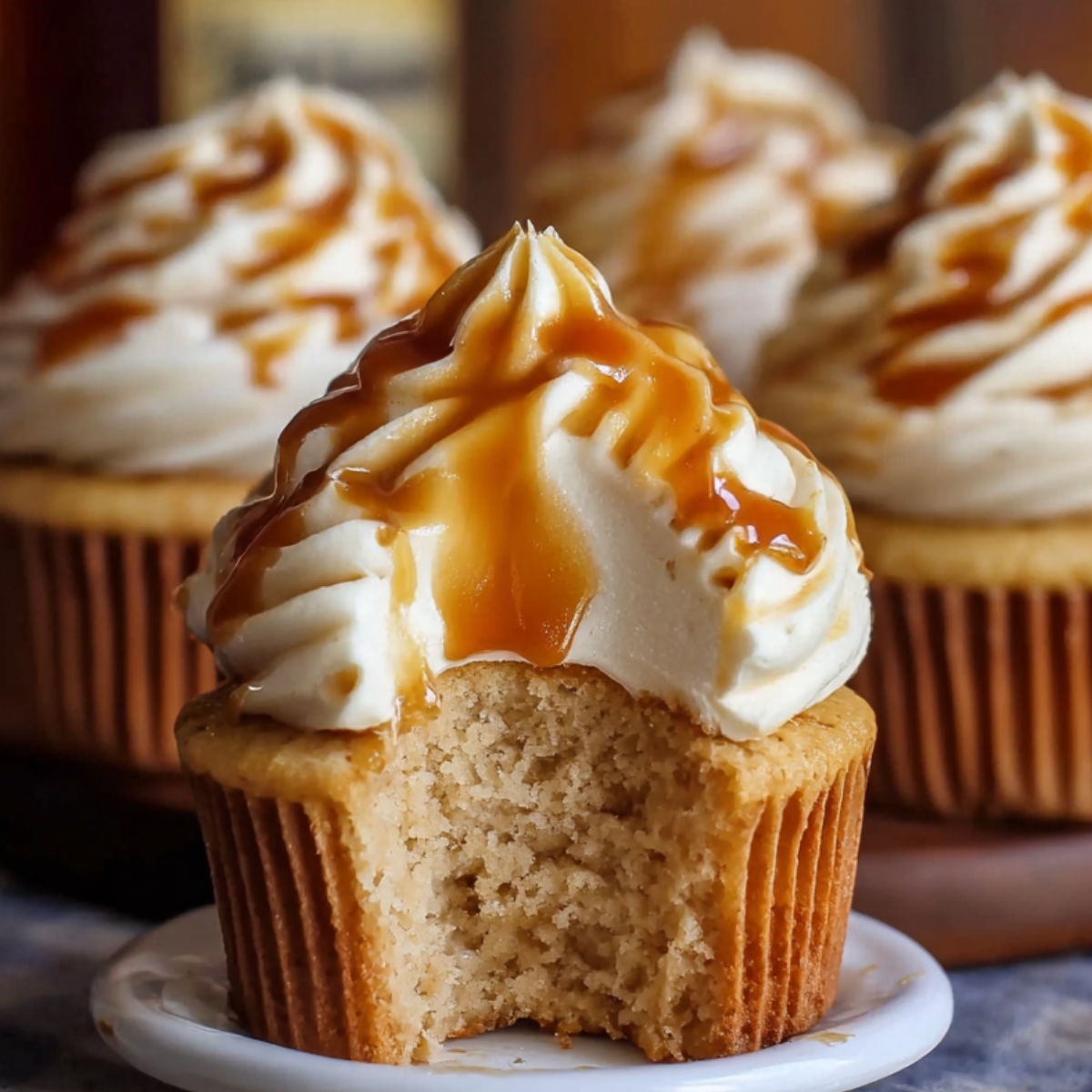 Homemade Harry Potter Butterbeer Cupcakes with creamy frosting and golden caramel drizzle, showing a soft, fluffy interior where a bite has been taken.