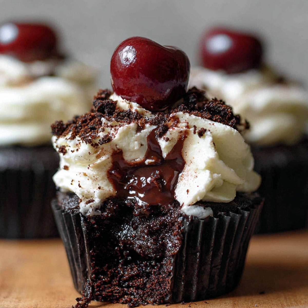 Black Forest Cupcakes with whipped cream, chocolate shavings, and a cherry on top, showing rich cherry filling oozing from the moist chocolate cake.