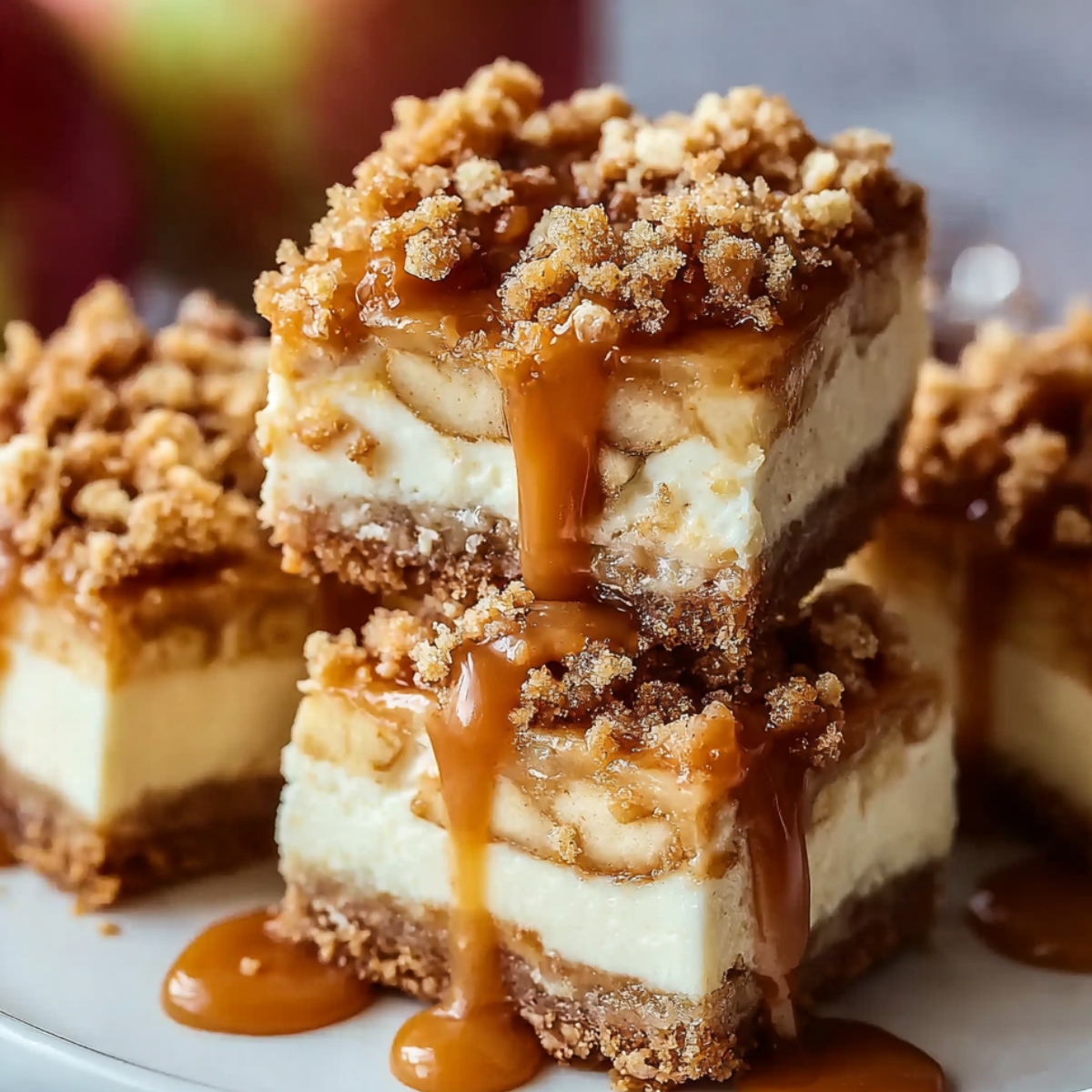 Caramel Apple Cheesecake Bars topped with crumble and dripping caramel sauce.