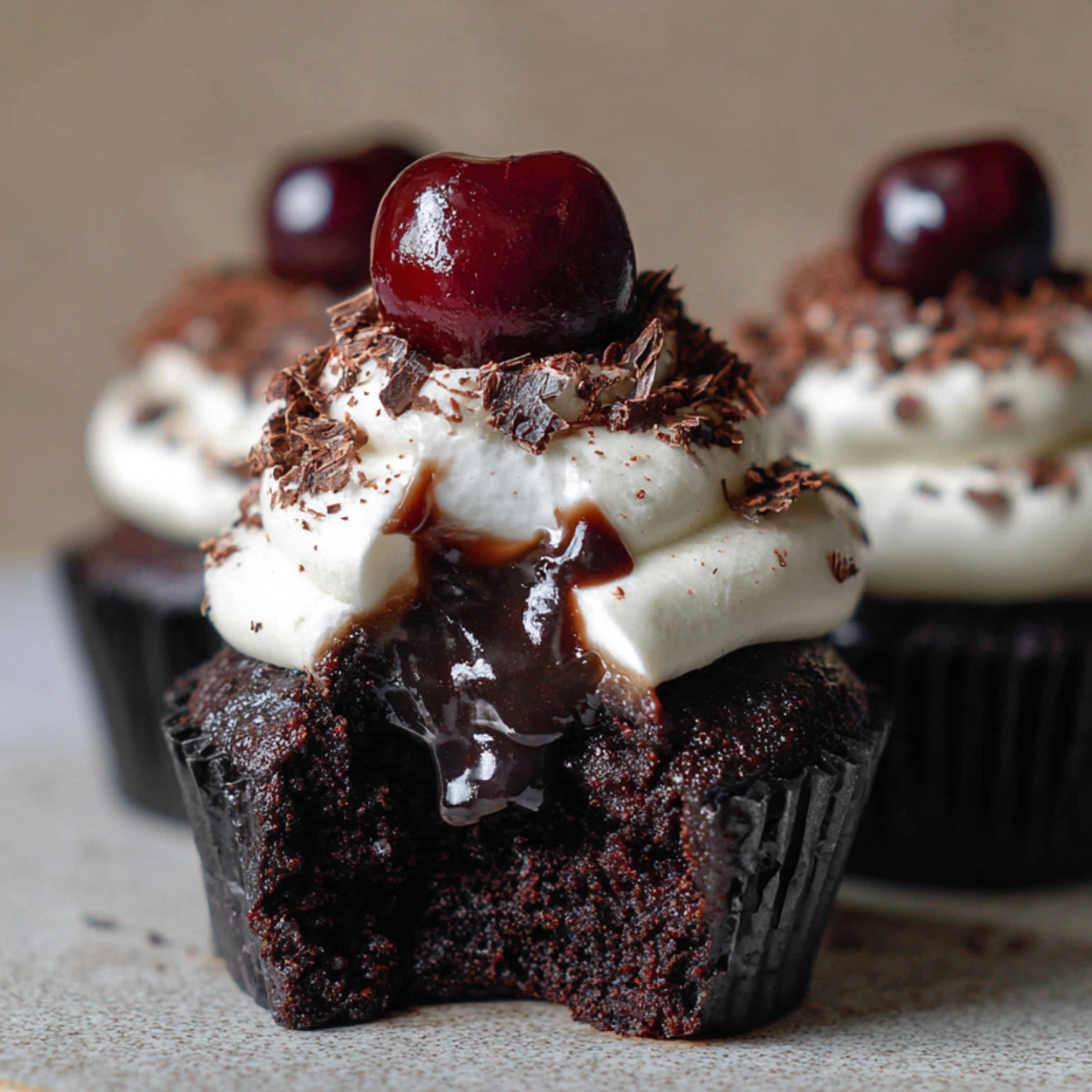 Homemade Black Forest Cupcakes with whipped cream, chocolate crumbs, and a cherry on top, showing rich chocolate and cherry filling inside a moist cake.