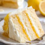 Homemade Lemon Curd Cake with layers of lemon filling and creamy frosting on a plate.