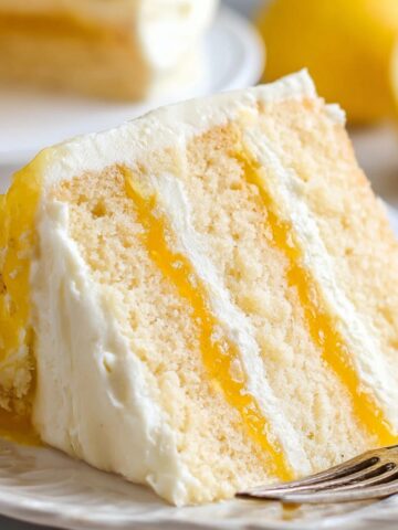 Homemade Lemon Curd Cake with layers of lemon filling and creamy frosting on a plate.