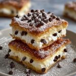 Homemade Ricotta Cannoli Squares stacked on a plate, filled with creamy ricotta and mini chocolate chips, topped with powdered sugar.