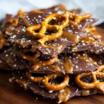 Homemade Salted Caramel Pretzel Bark, showing jagged pieces of dark chocolate coated in gooey caramel, topped with whole crunchy pretzels and sprinkled with flaky sea salt.