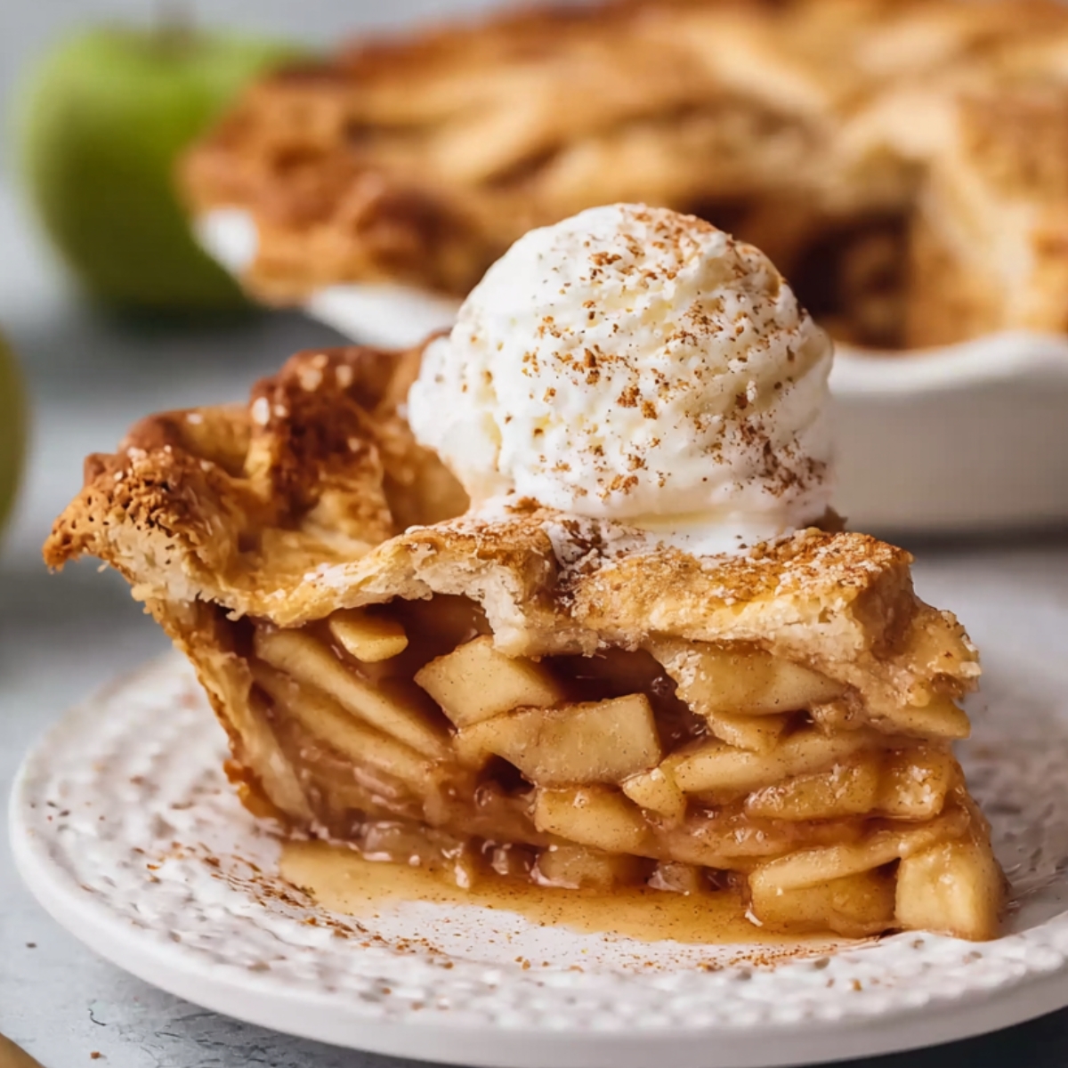 Homemade Vegan Apple Pie topped with a scoop of vanilla ice cream and cinnamon on a white plate.
