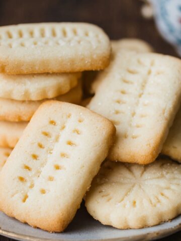 Shortbread Cookies on a plate, lightly golden with a dusting of sugar and traditional fork-docked holes.
