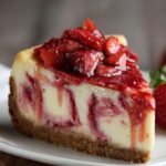 Strawberry Swirl Cheesecake topped with fresh strawberry sauce on a graham cracker crust.