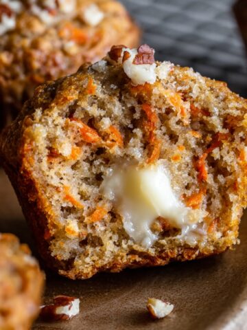 Banana Carrot Muffins with a moist, crumbly interior and a dollop of melted butter, topped with pecans.