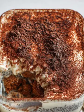 Close-up of homemade tiramisu chia pudding with cocoa-dusted top, featuring round cocoa-covered spheres and creamy layered pudding inside.