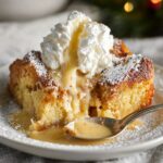 Eggnog Bread Pudding with whipped cream and warm vanilla sauce on a white plate.