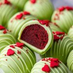 Grinch Oreo Balls with red velvet inside, decorated with red heart sprinkles and a swirl pattern.