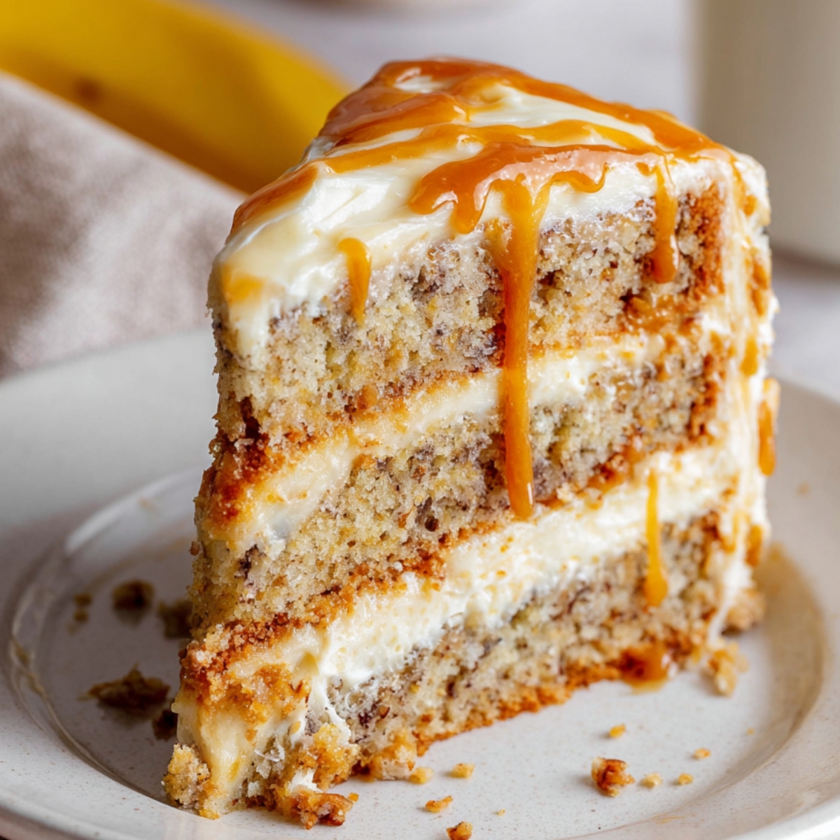 Homemade Banoffee Cake with banana sponge, cream layers, and caramel drizzle.