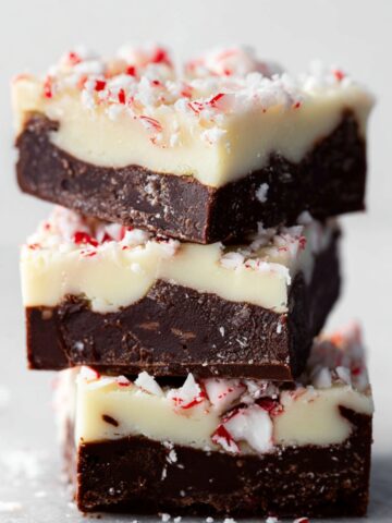Homemade Peppermint Bark Fudge with dark chocolate base and white chocolate top, sprinkled with crushed peppermint pieces.