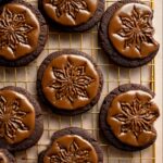 Stamped Chocolate Espresso Cookies topped with glossy espresso glaze and stamped floral designs, cooling on a gold wire rack.