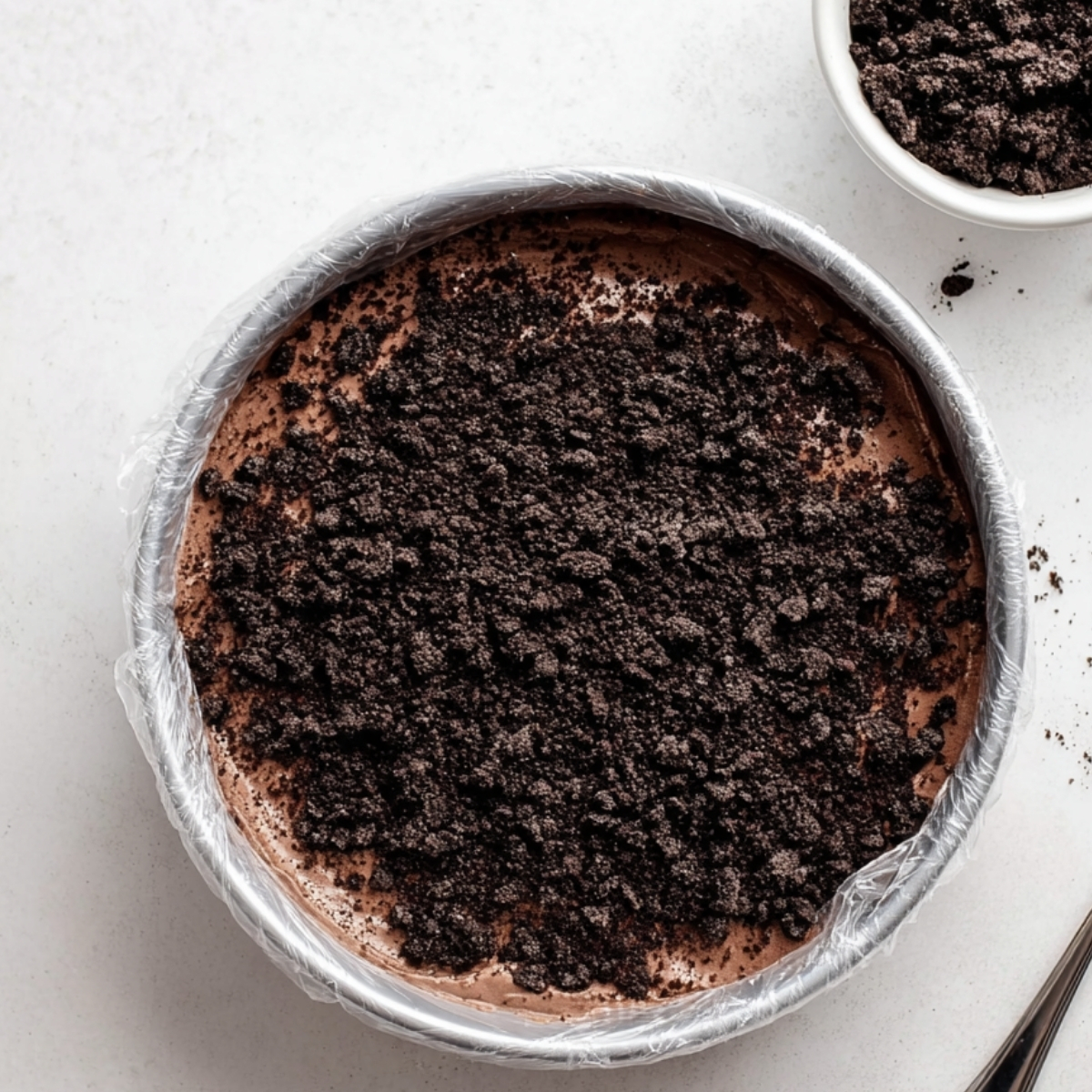 Homemade Ice Cream Cake Recipe | 6 Ingredients, No Bake 12 Crushed Oreo cookie layer sprinkled over chocolate ice cream base in a cake pan