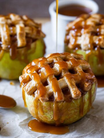 Apple Pie Baked Apples 2 Apple Pie Baked Apples with a golden lattice crust, topped with a generous drizzle of caramel sauce, ready to be served as a warm, indulgent dessert.