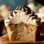 A close-up of a freshly baked Baileys and Coffee Cupcakes with fluffy buttercream frosting topped with chocolate sprinkles, showcasing its soft crumb.