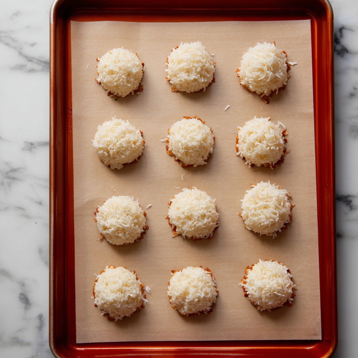 A baking sheet with evenly spaced coconut macaroons, ready for baking.