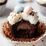 Coconut Chocolate Easter Cupcakes with coconut frosting, pastel candy eggs, and a chocolate ganache filling inside.