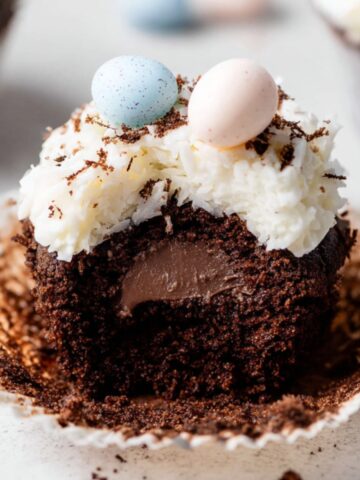Coconut Chocolate Easter Cupcakes 4 Coconut Chocolate Easter Cupcakes with coconut frosting, pastel candy eggs, and a chocolate ganache filling inside.