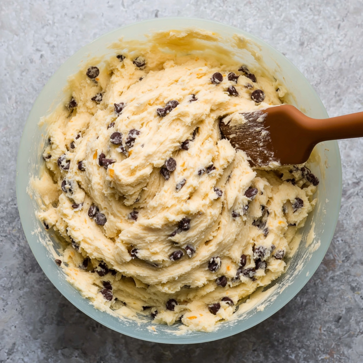 Orange Chocolate Chip Ricotta Cookies 10 A large mixing bowl filled with soft, creamy orange chocolate chip ricotta cookie dough, with chocolate chips evenly distributed throughout the mixture.