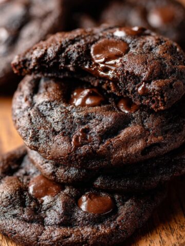 Stack of soft Double Chocolate Chip Cookies with melted chocolate chips on a wooden board