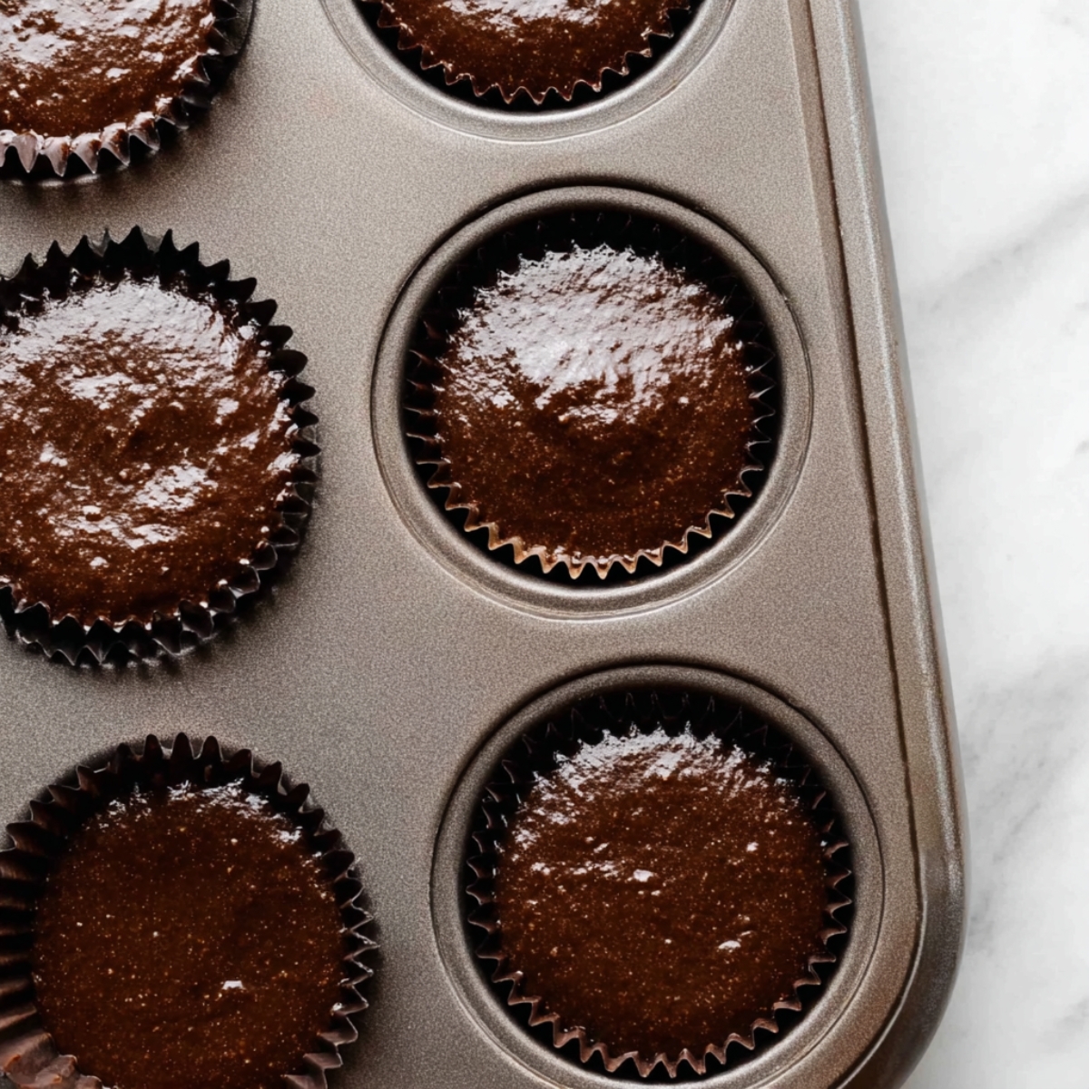 Cream-Filled Chocolate Cupcakes 11 Chocolate cupcake batter portioned into lined muffin tin ready for baking