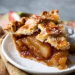 Homemade Caramel Pear Pie with a golden lattice crust, showing a gooey, caramelized pear filling inside.